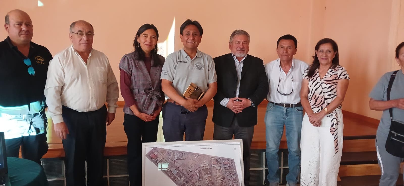Participantes posan con un cuadro en una sala.